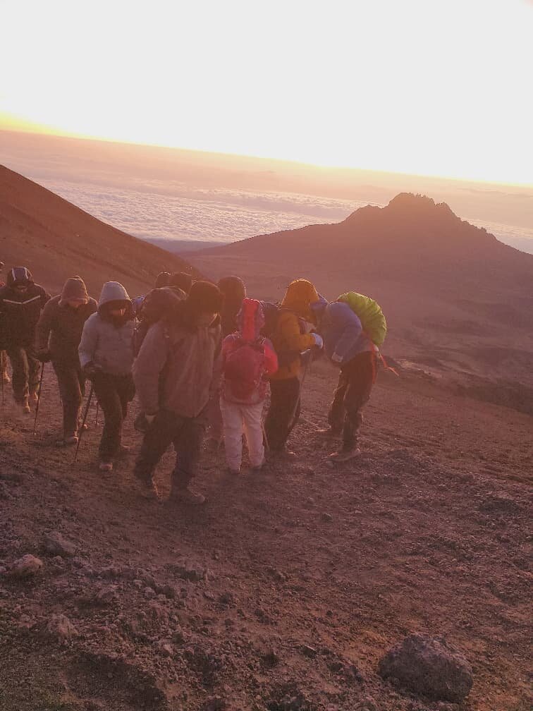 Group of trekkers climbing scree at dawn on Mount Kilimanjaro
