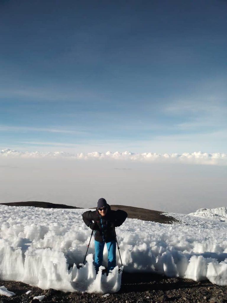 Lone trekker beside a field of ice penitentes above the clouds on Mount Kilimanjaro