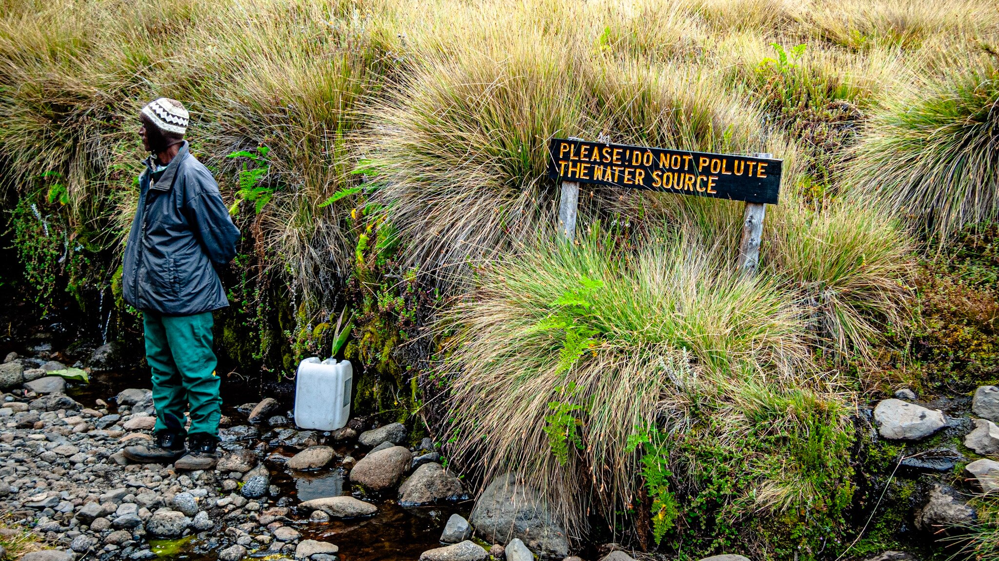 Porter with jerrycan at water source sign on Mount Kilimanjaro
