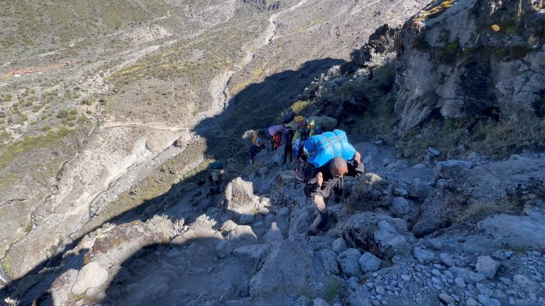 Porters carrying loads up rocky trail on Mount Kilimanjaro
