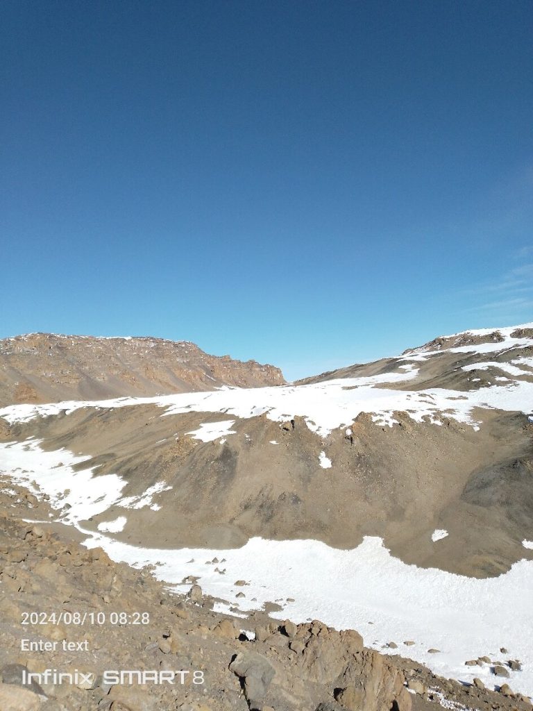 Snowfield and dark scree inside the summit crater of Mount Kilimanjaro
