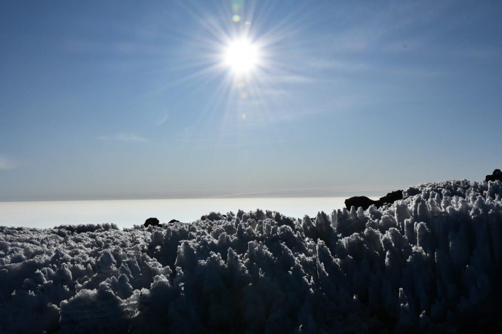 Sun starburst above a field of spiky penitentes ice on the summit of Mount Kilimanjaro