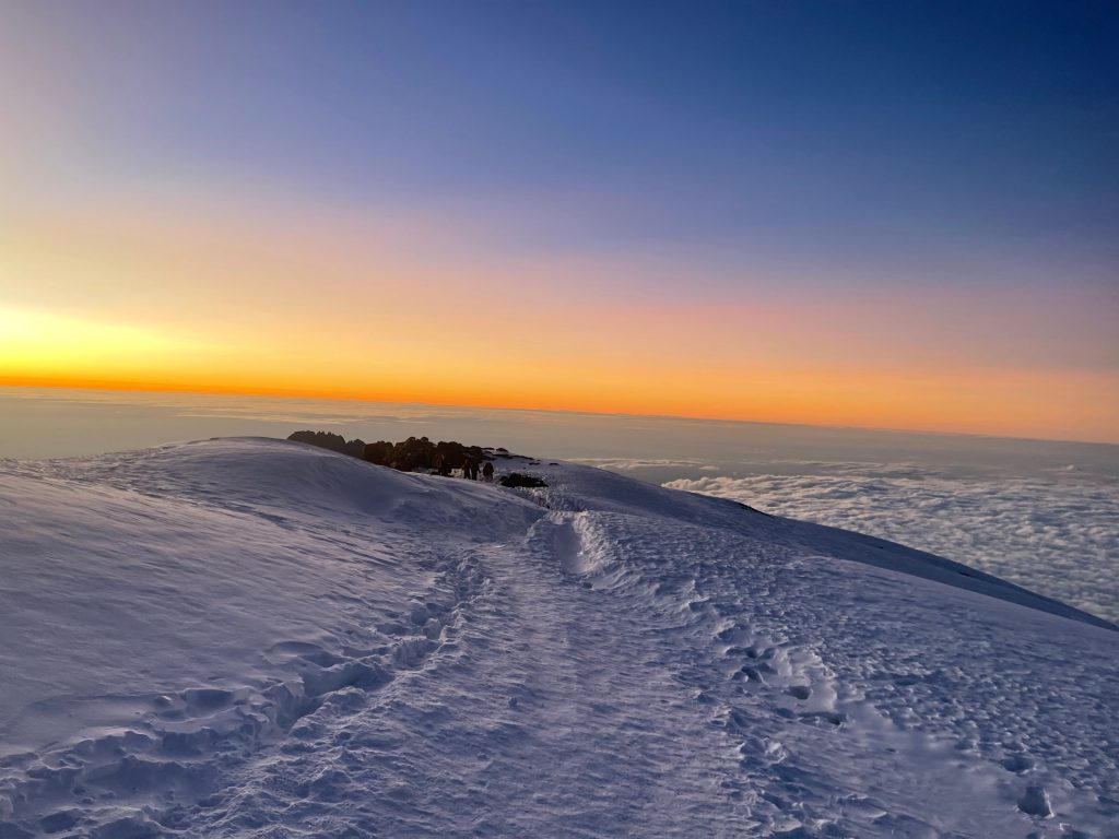Trail along snowy crater rim at sunrise on Mount Kilimanjaro