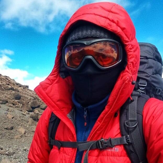 Trekker in red jacket and ski goggles on Mount Kilimanjaro