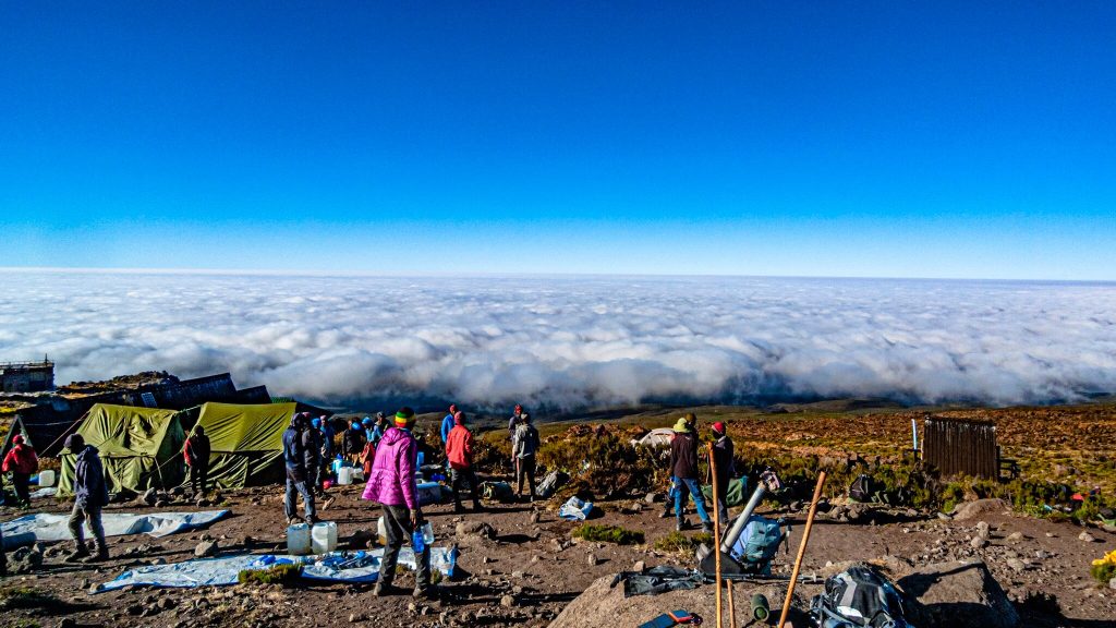 Trekkers and porters at camp above clouds on Mount Kilimanjaro