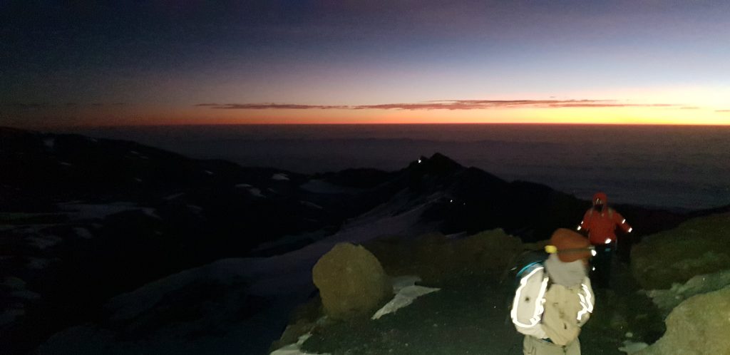 Two trekkers on summit ridge predawn glow on Mount Kilimanjaro