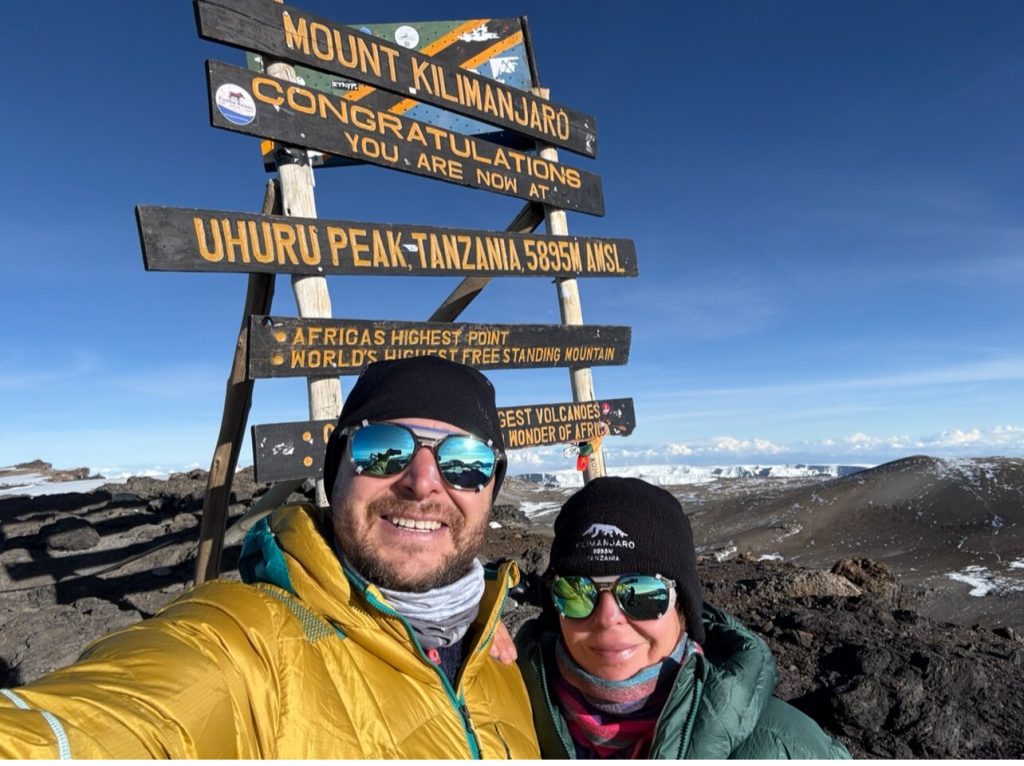 Two trekkers selfie at uhuru peak sign on Mount Kilimanjaro